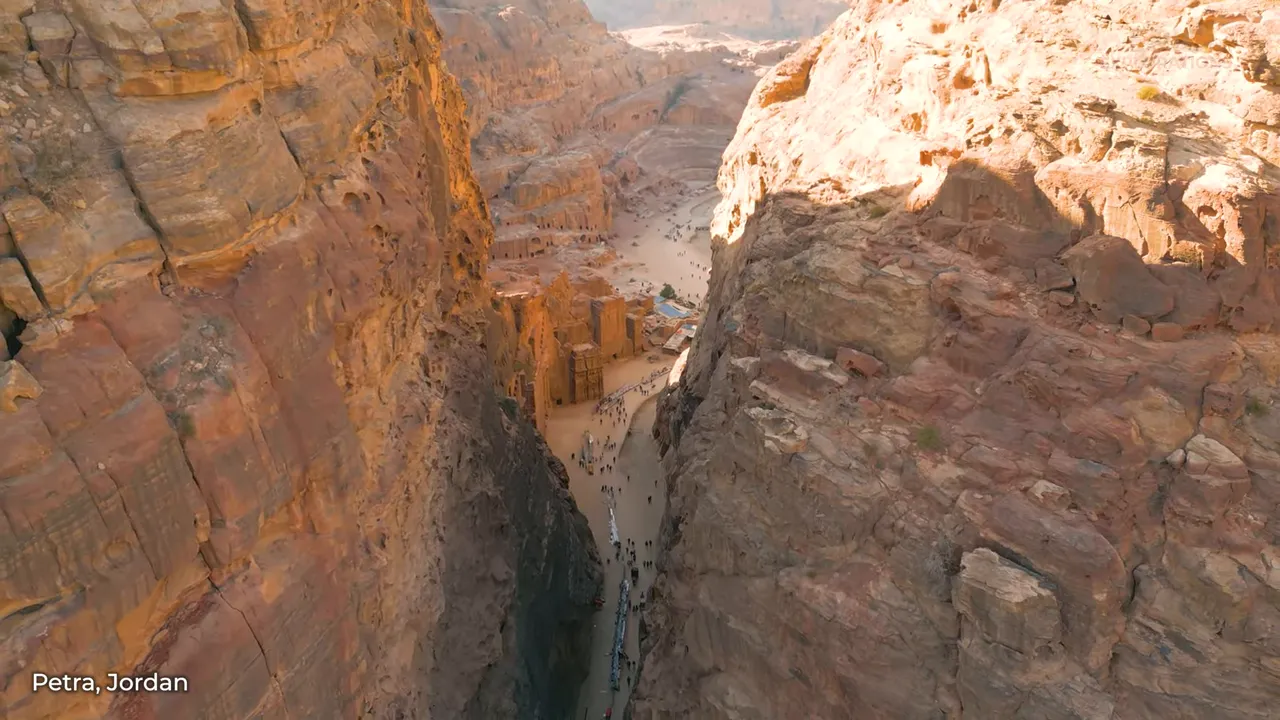 The rose-hued rock facade of Petra's Treasury viewed through the Siq