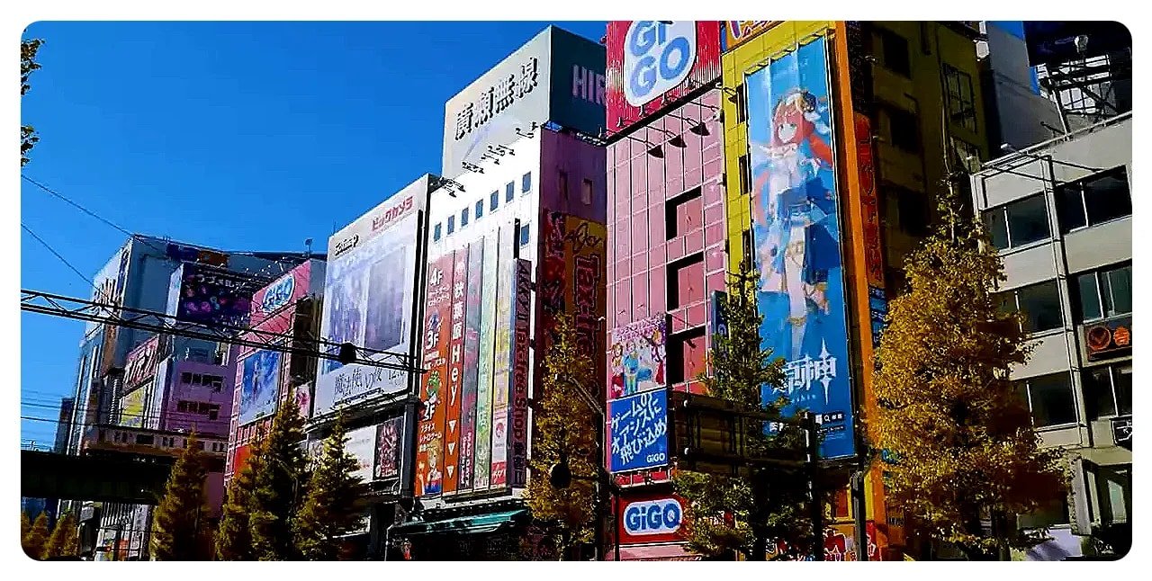 Row of colorful Akihabara buildings with tall anime and game advertisements