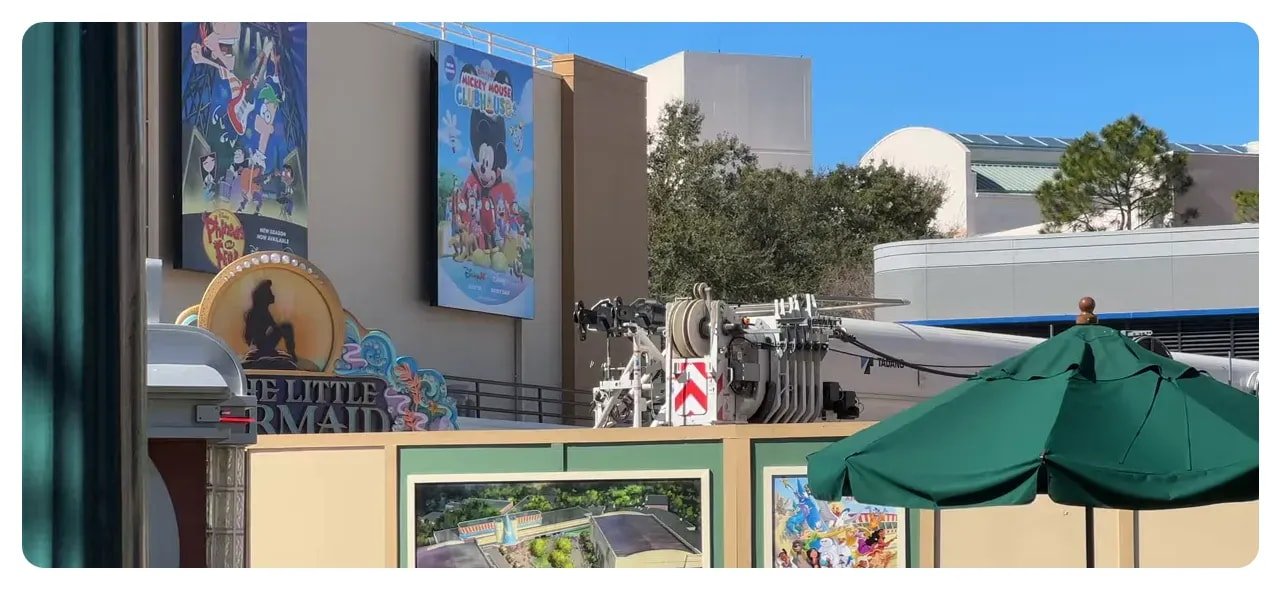 Close-up of construction hoarding with concept art panels and equipment behind the fence