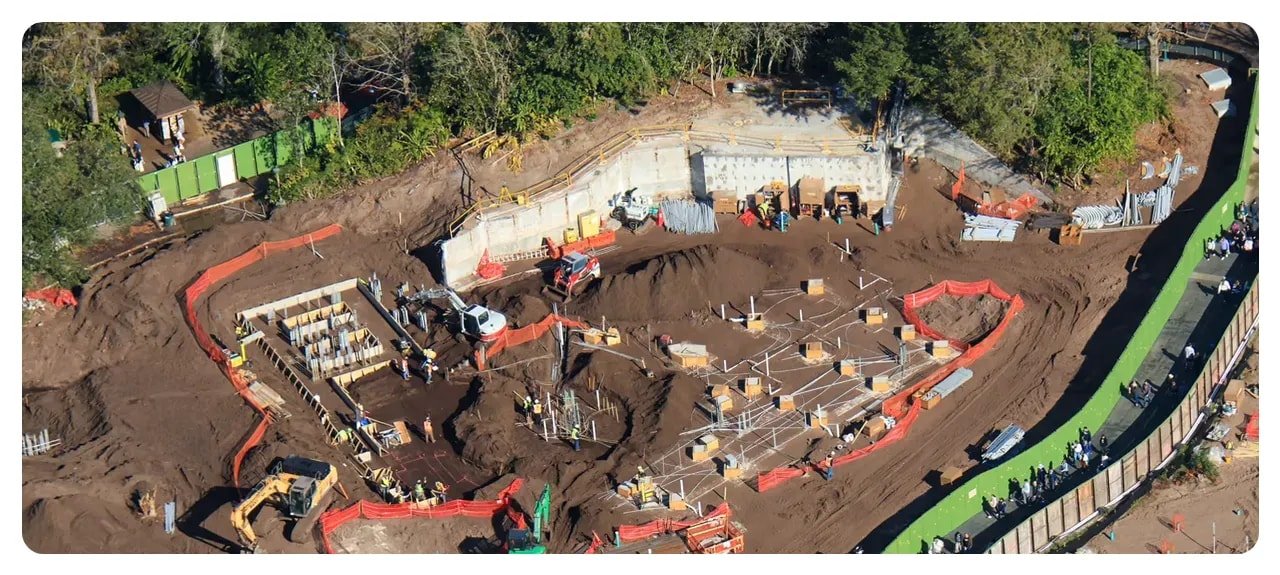 Close-up aerial of cleared footprint with foundation forms, footings, and construction equipment at a Disney park site.