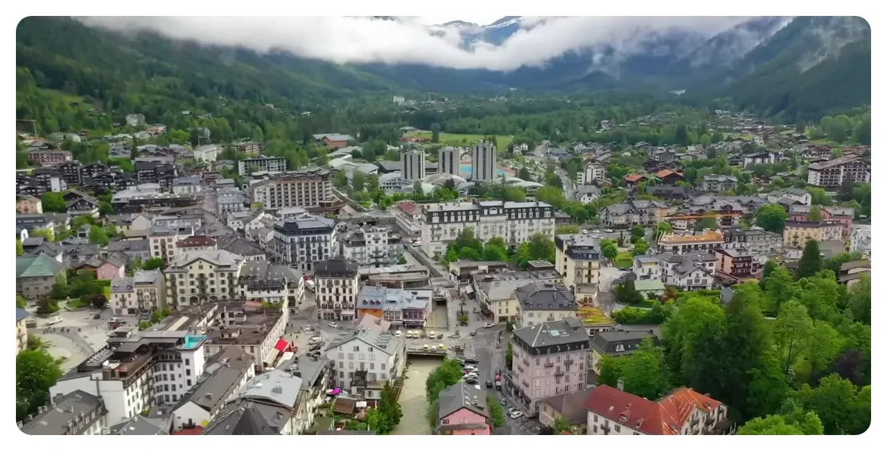 Aerial view of Chamonix town centre with buildings, river channel and misty mountains in the background