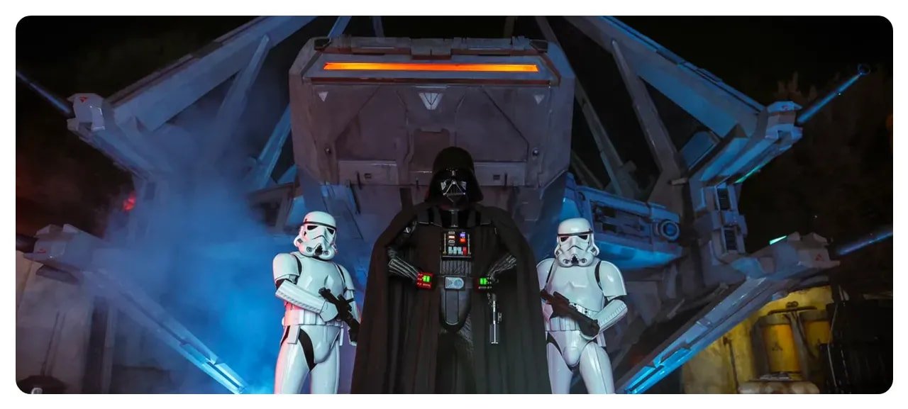 Darth Vader flanked by two stormtroopers in Galaxy's Edge at night