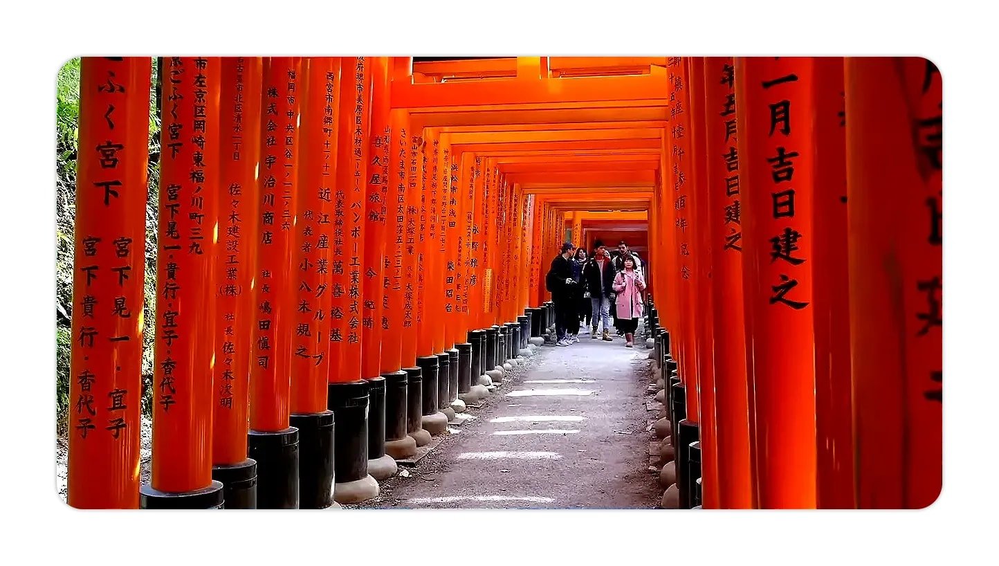 Path through bright orange torii gates of Fushimi Inari Shrine with Japanese inscriptions on the pillars