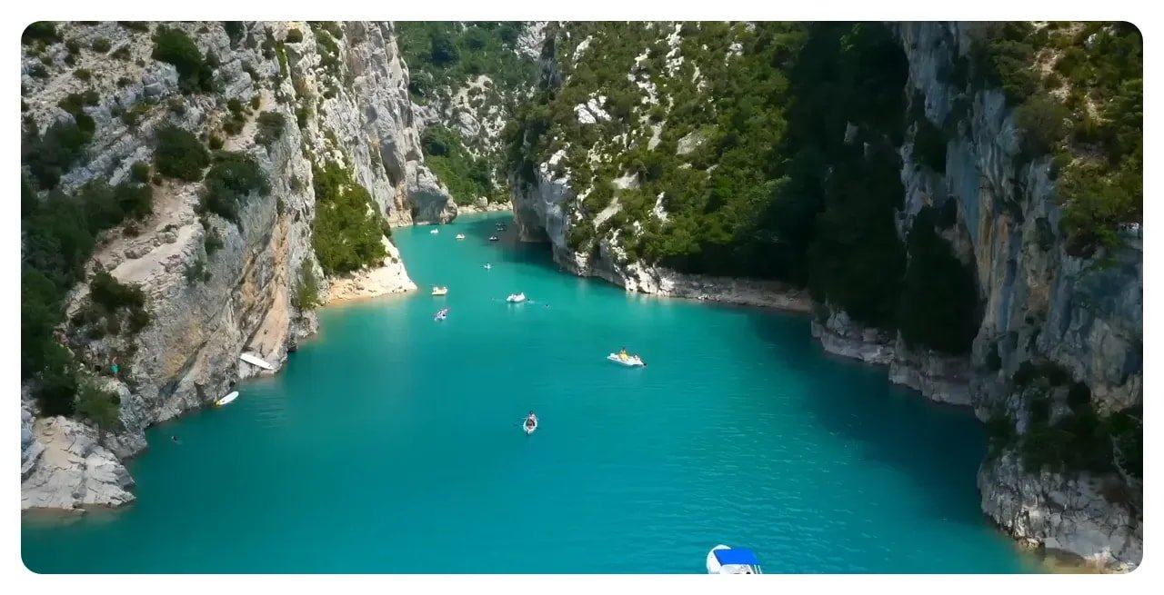 Deep narrow section of Gorges du Verdon with vivid turquoise water and kayaks between limestone cliffs
