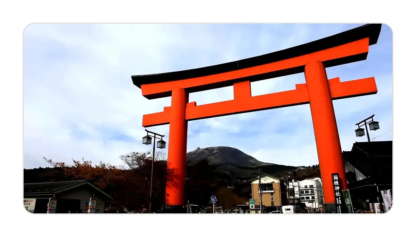Red torii gate in front of a mountain and town buildings, clear and high quality