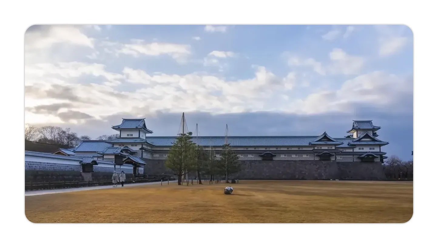 Kanazawa Castle with open lawn and moat under a cloudy sky
