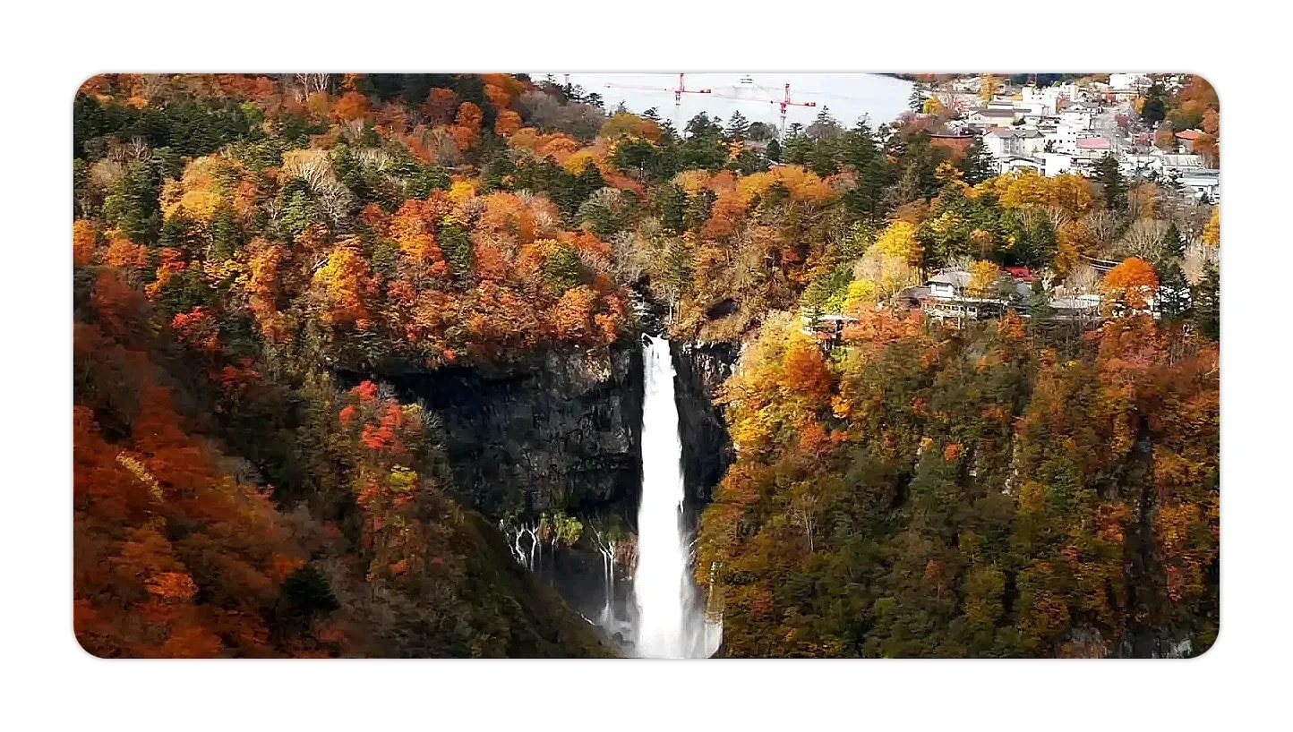 Tall waterfall dropping between steep cliffs framed by orange and red autumn trees