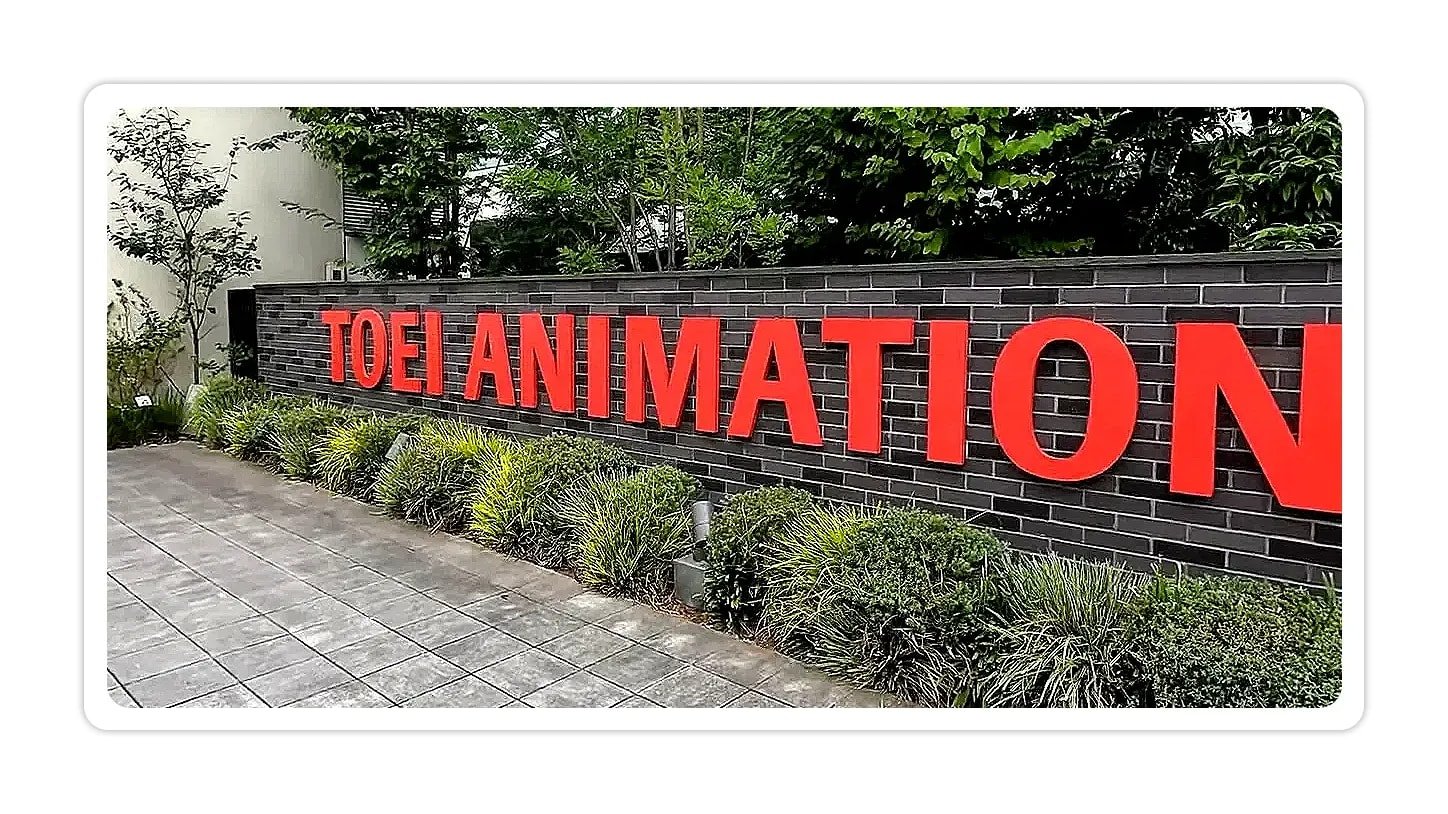 Close-up of red TOEI ANIMATION letters mounted on a brick wall with plants