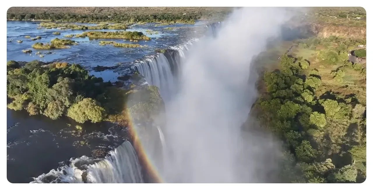 High-resolution aerial image of Victoria Falls showing the cascading falls, thick mist plume and a rainbow over the gorge